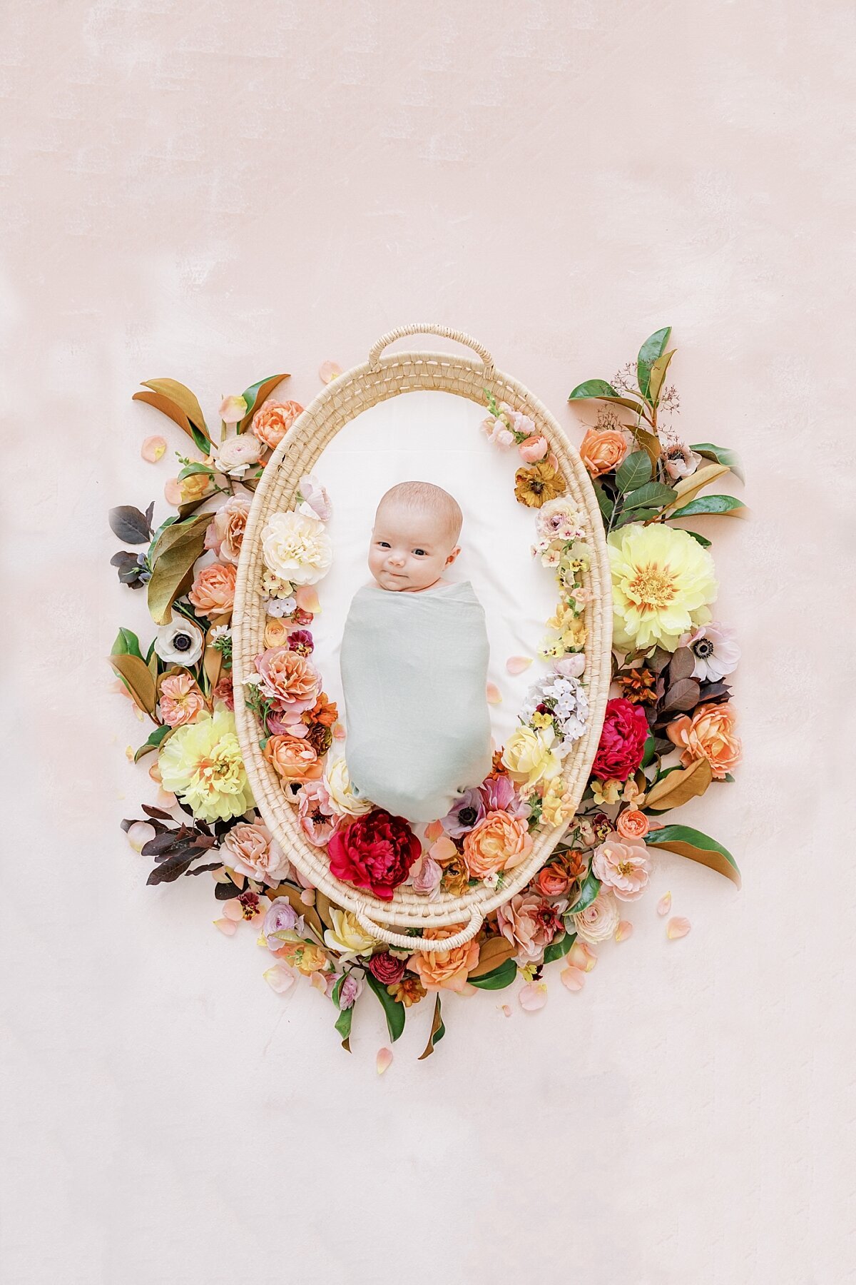 newborn girl with flowers around her in a basket