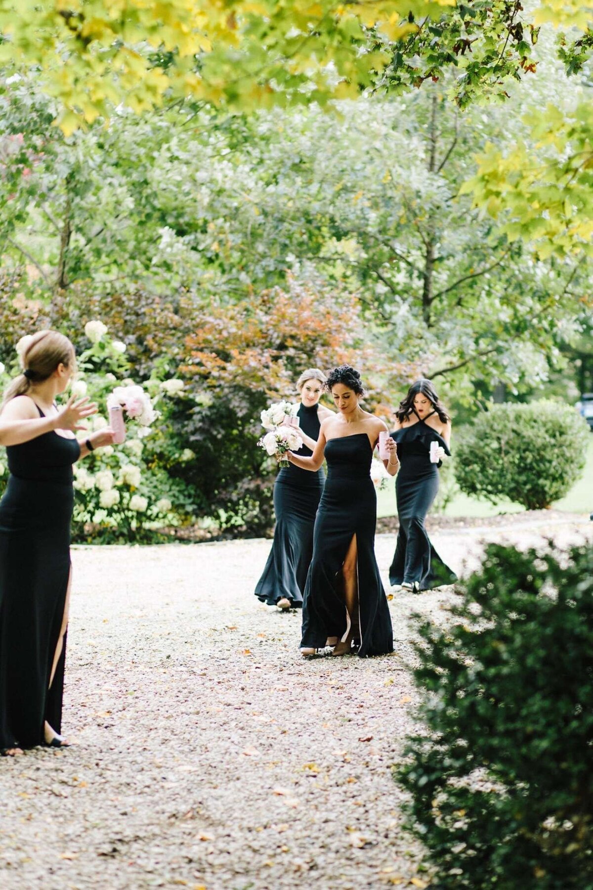 Bridesmaids in Elegant and Timeless Floor Length Black Gowns walk to a Luxury Michigan Lakefront Golf Club Wedding.