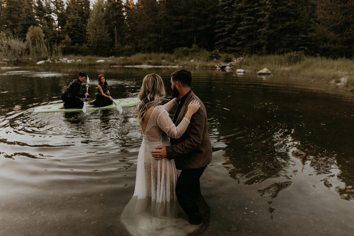 newlyweds playing in a pond with their kids in wedding attire