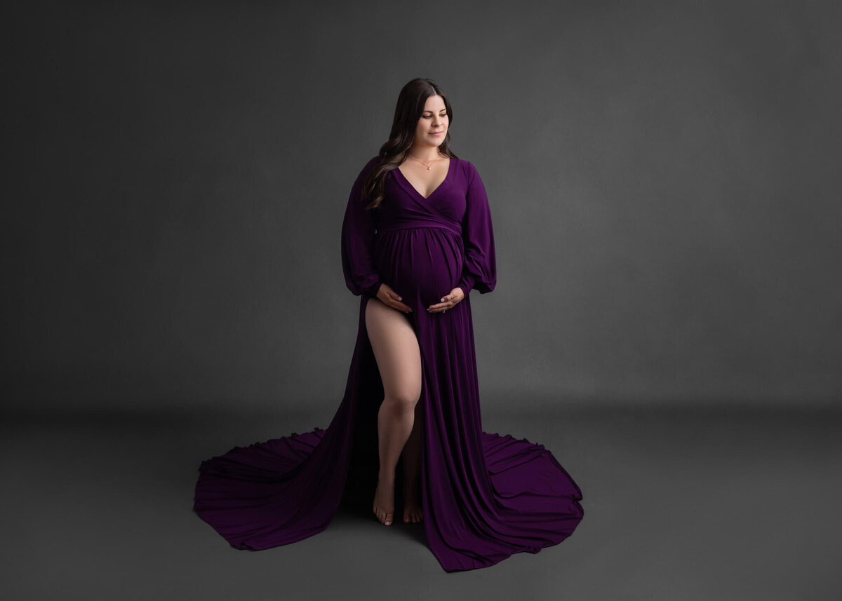 prengnant mom in purple dress cradling her belly