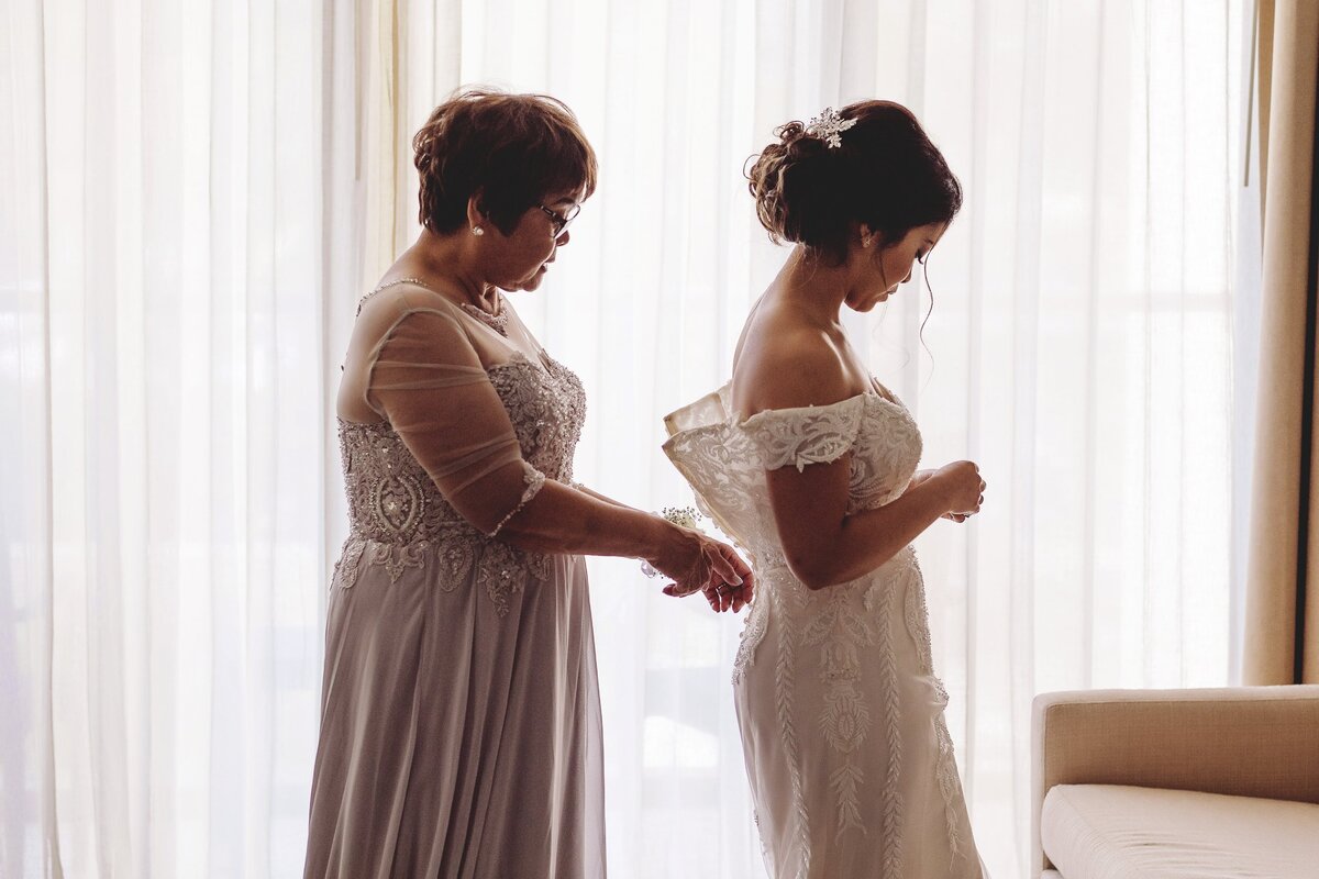 Mother helping bride into dress at Cancun Wedding