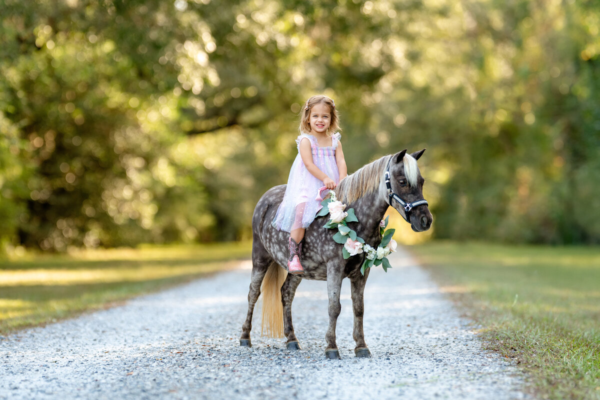 Child riding her miniature horse bareback. Photo taken by professional photographer in  Fairhope, AL.