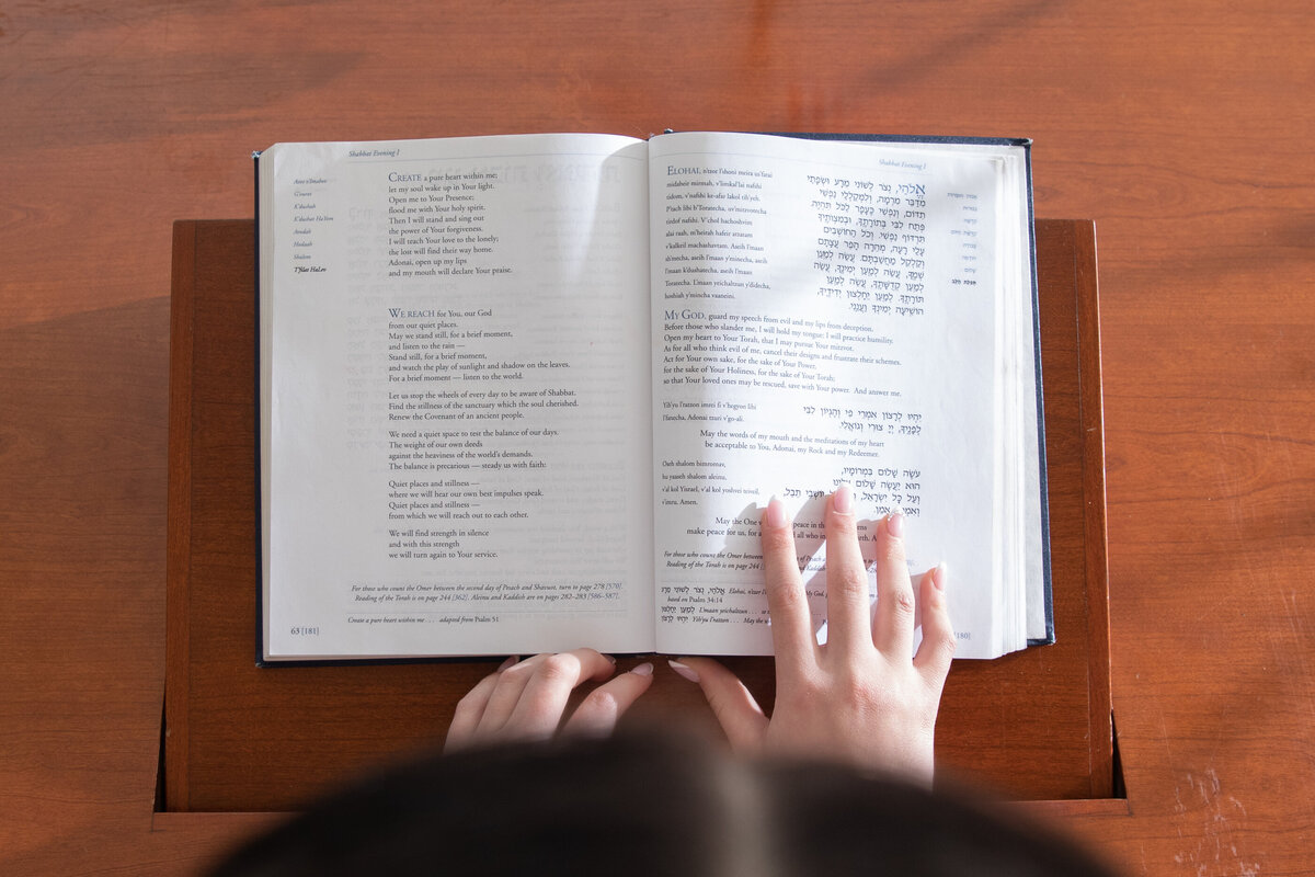 detail shot of a teenage girl's hand pointing to a prayer book at Tempe Avodah Long Island bat mitzvah photographer Milestone Images
