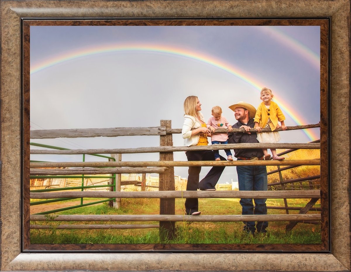 Family with two small girls standing by a fence looking at a rainbow in Cheyenne Wyoming.