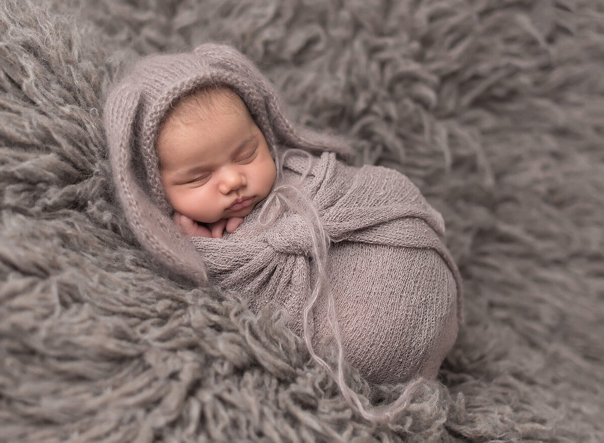 Wrapped newborn in grey fur background