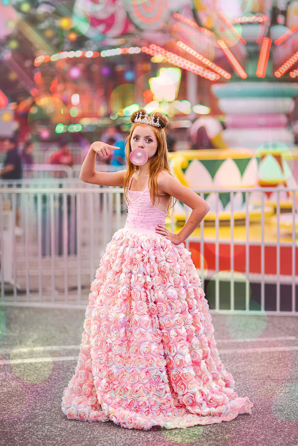 Red haired girl in a rainbow pink dress at a carnival blowing a bubble gum bubble near Annapolis Maryland