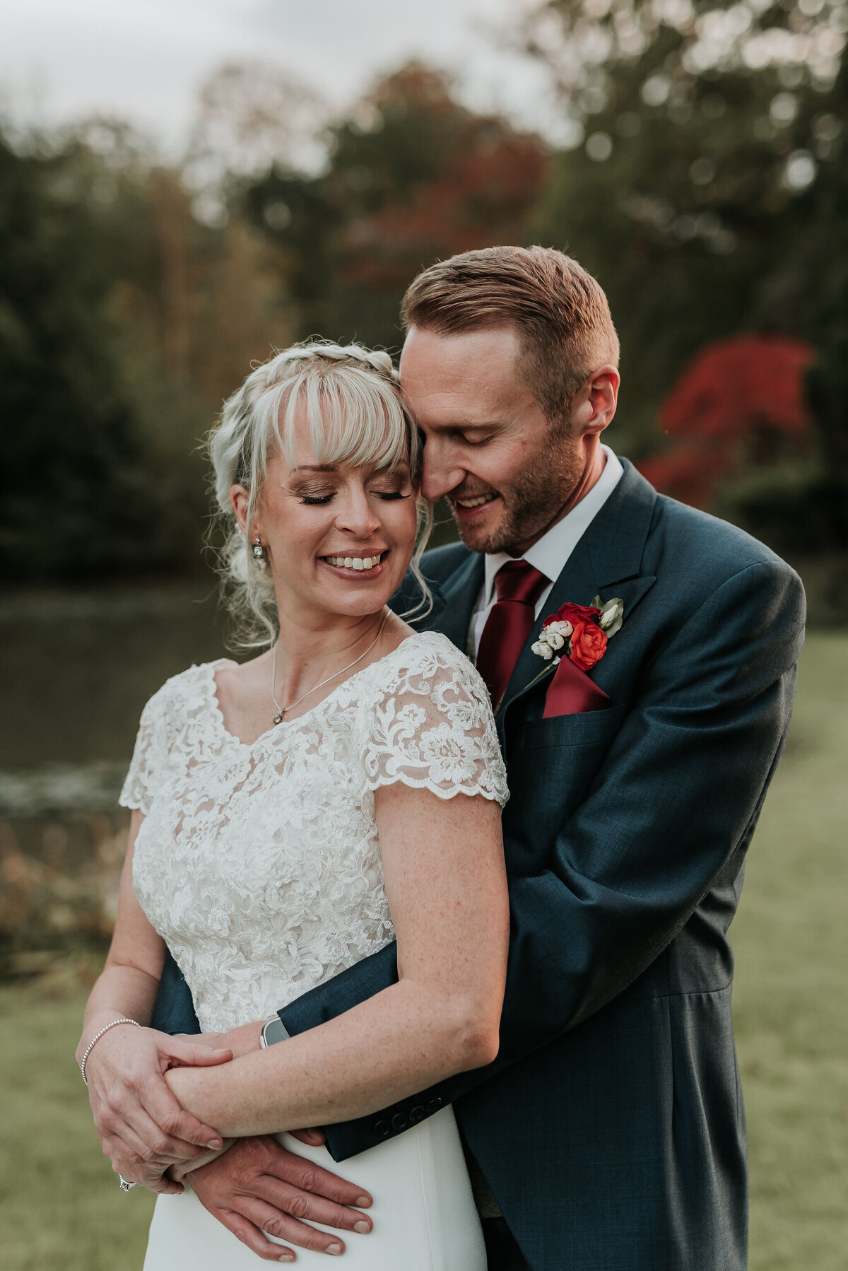Groom embraces his Bride gently at their joyful autumn wedding at The Ravenswood