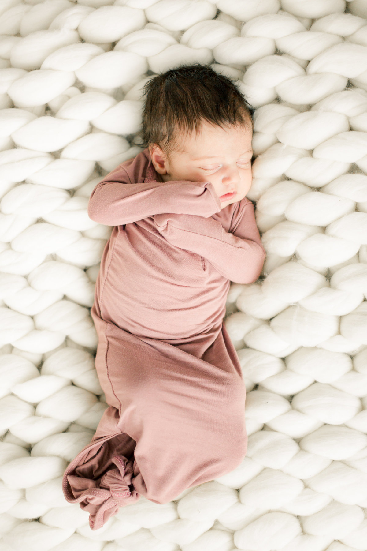 baby lays on chunky white wool blanket for newborn portraits