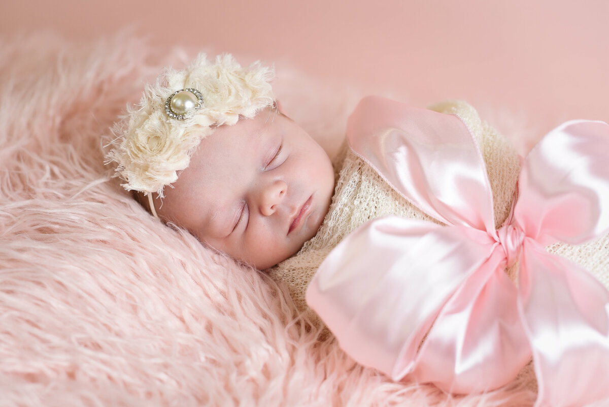 Beautiful Mississippi newborn photography: newborn girl red wrapped with a pink gift ribbon, Mississippi Newborn Photographer