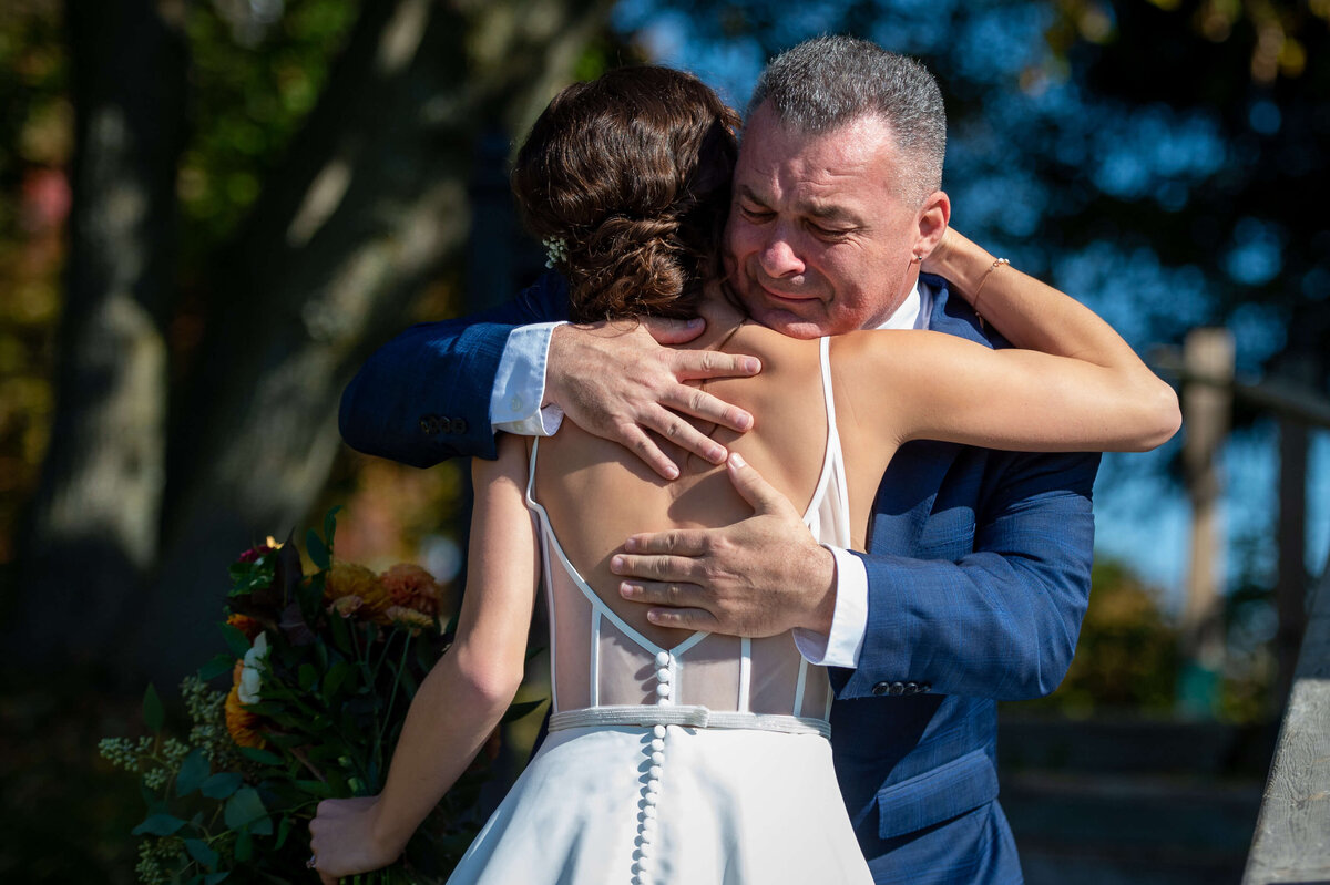 Ottawa wedding photography of a father emotionally hugging his daughter when he sees her for the first time.  Captured by Ottawa wedding photographer JEMMAN Photography at Strathmere wedding venue.