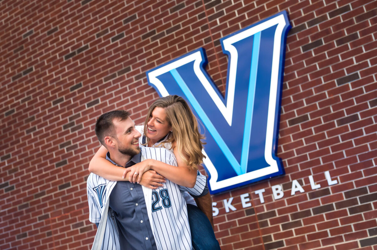 Woman on the back of a man wearing a baseball jersey in front of Villanova university