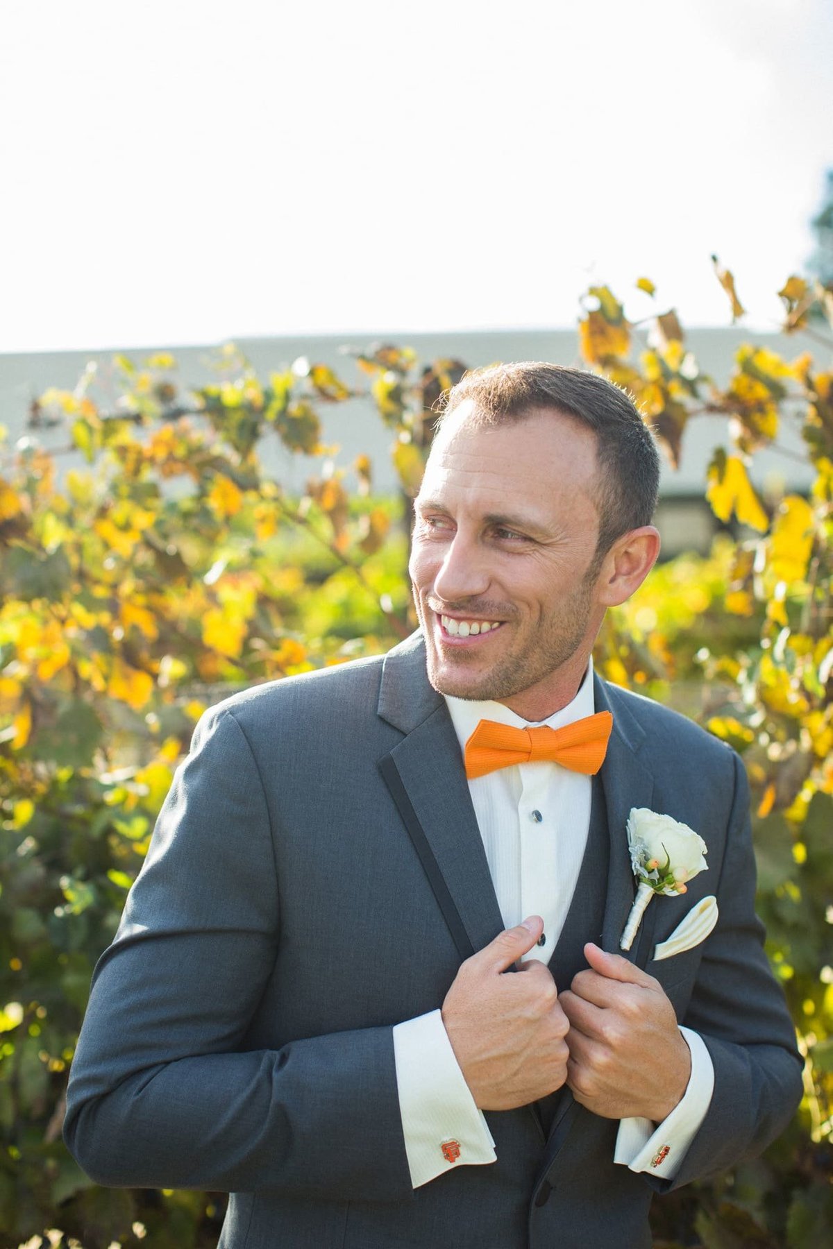 Groom poses with a large smile in the fields