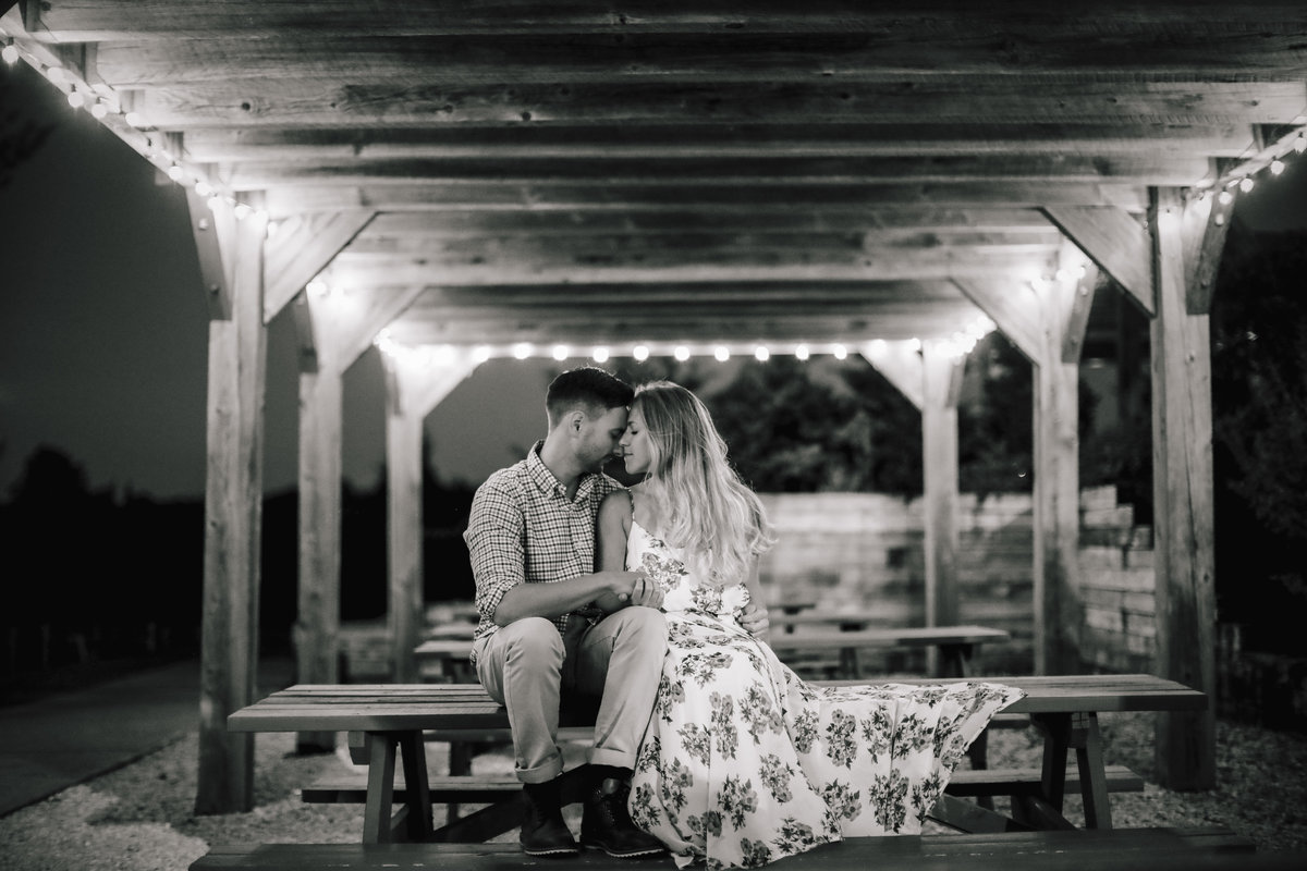 engaged couple cuddle in barn in laurita winery