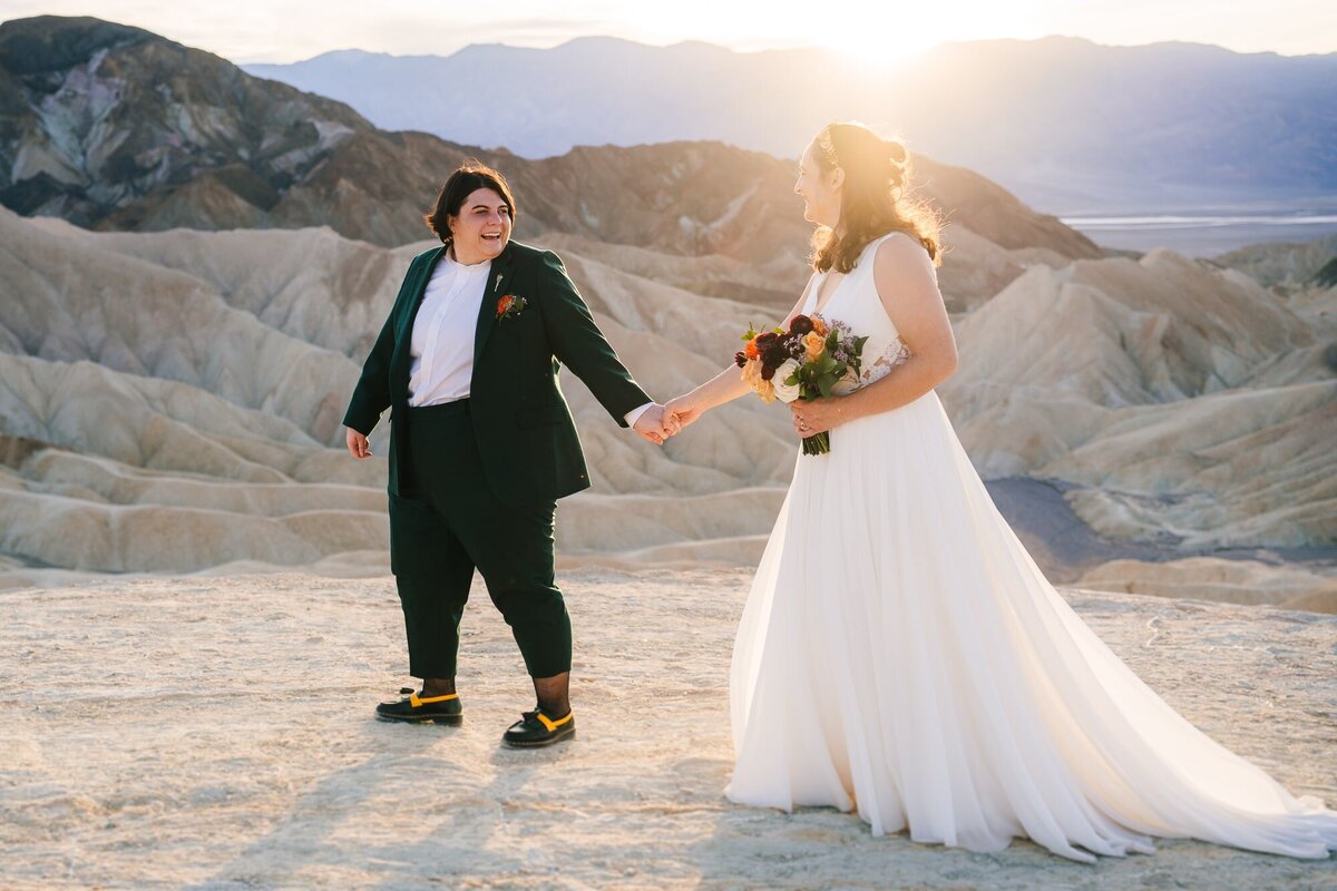 A breathtaking elopement photo captured at Zabriskie Point in Death Valley, where the couple strolls hand in hand with a stunning backdrop that adds to the beauty of their love story.