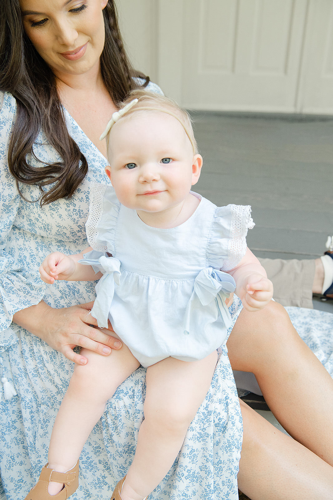A woman is holding a baby in a blue dress.
