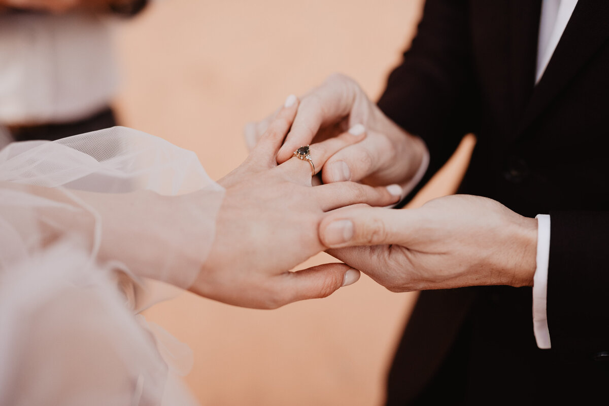 Utah elopement photographer captures groom putting ring on partner's finger