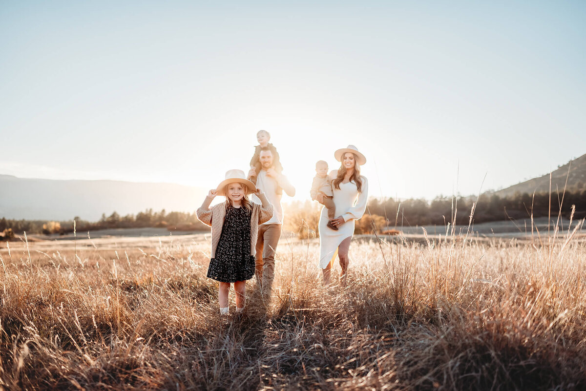 little girl leading her family through a field in front of denver foothills photography