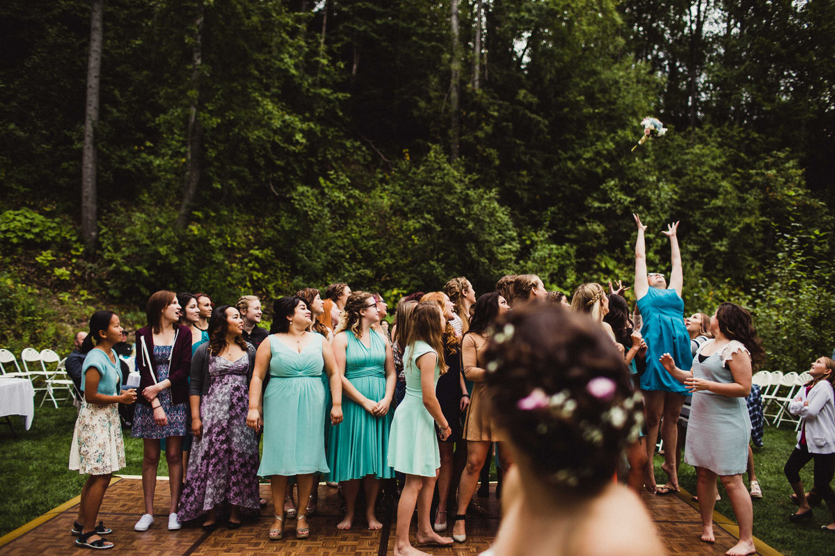 woman jumps high above everyone else to catch bouquet at backyard wedding