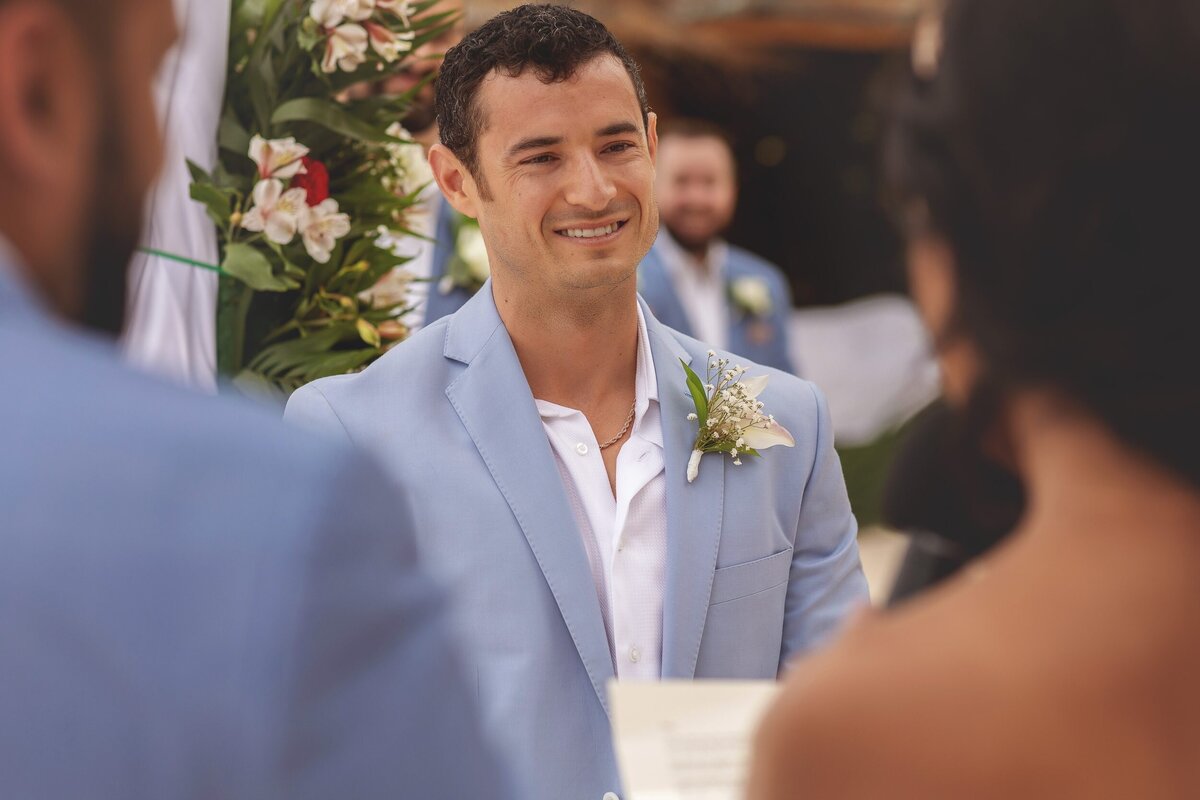 Groom smiling at bride as she says her vows at  Riviera Maya wedding.
