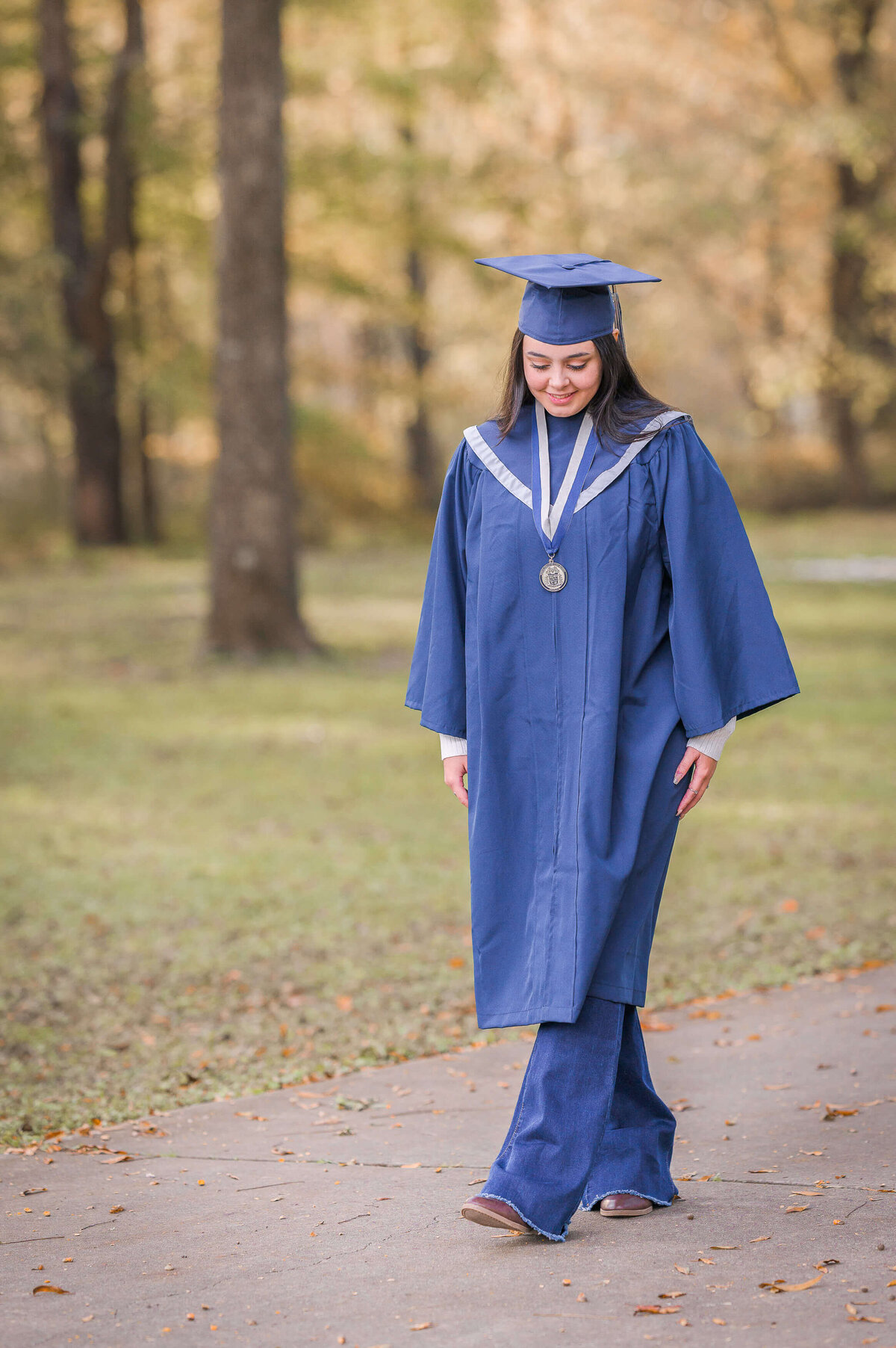 girl  walking wearing  her North Paulding high school cap and gown for her senior photos