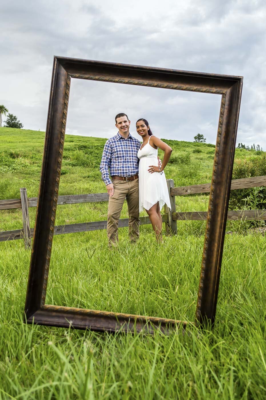 Engaged couple poses framed by a large wooden frame