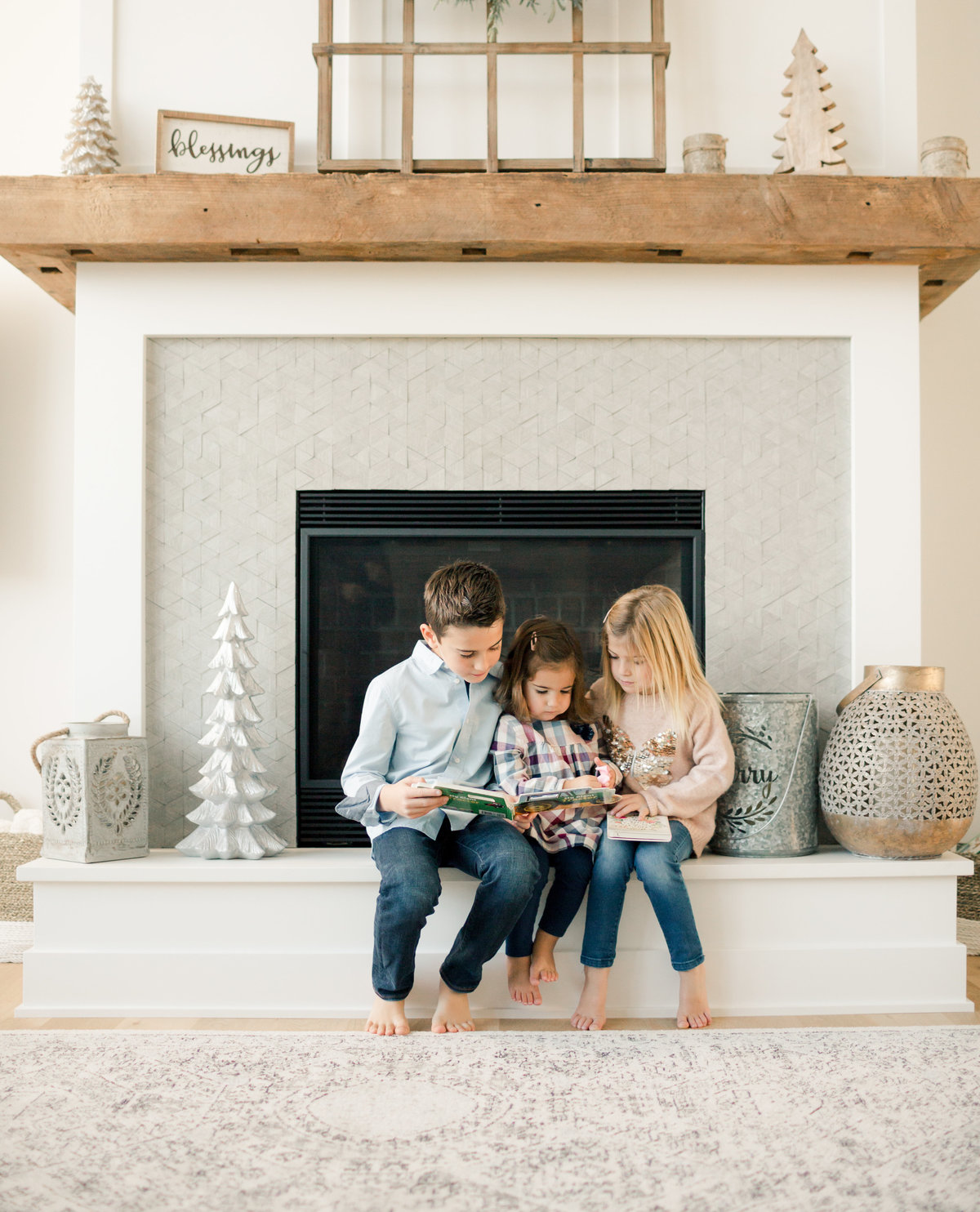 siblings read book to two year old sister in front of fireplace
