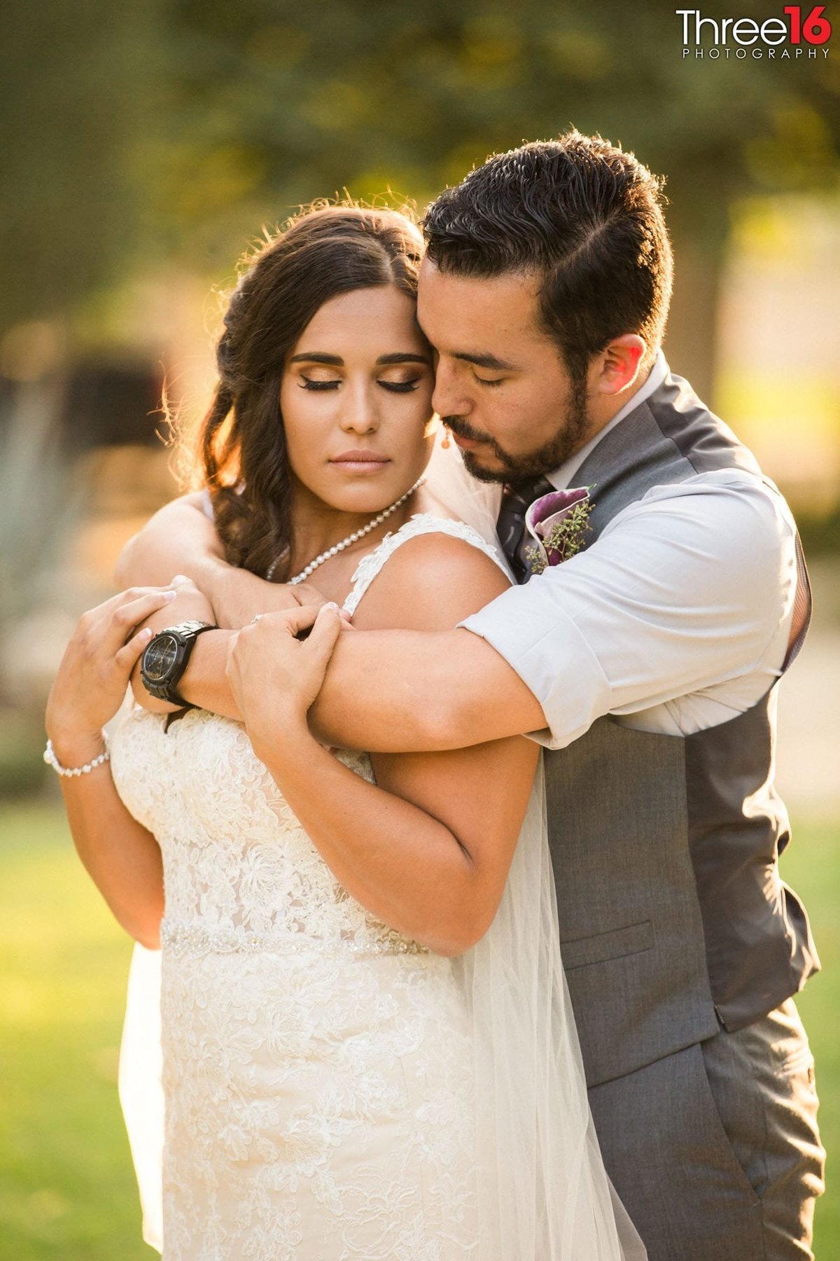 Tender moment as the Bride is fully embraced from behind by her Groom during after wedding photo session
