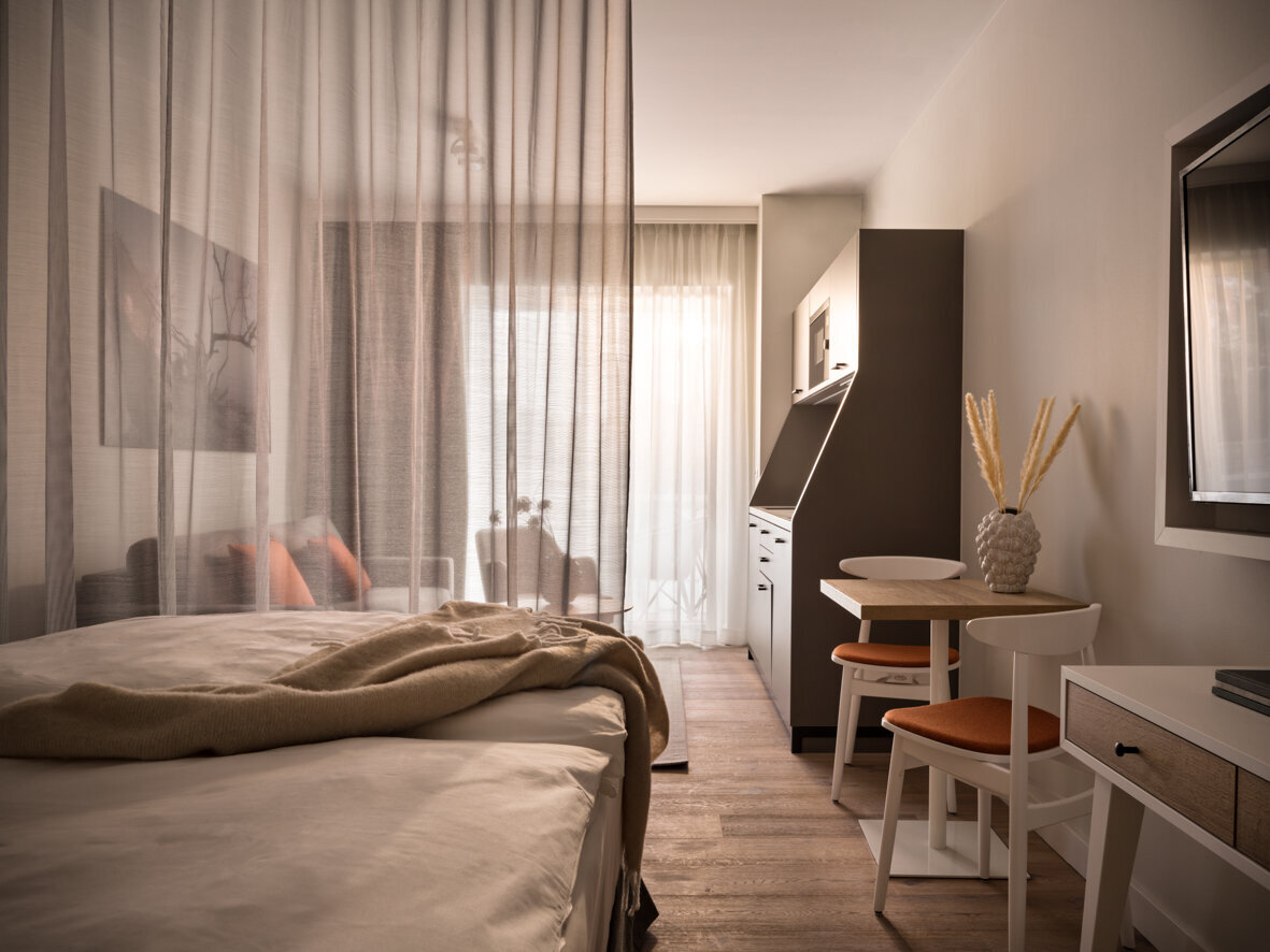 Blick in das Apartment Studio Living mit Doppelbett, kleinem Essbereich und Küchenzeile.