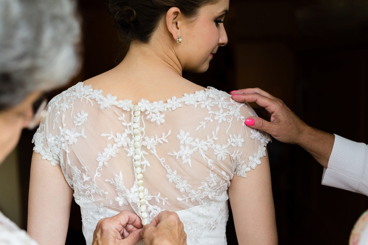 The bride gets her dress buttoned by her mom and grandmother on the day of her elopement at Loon Mountain Resort NH