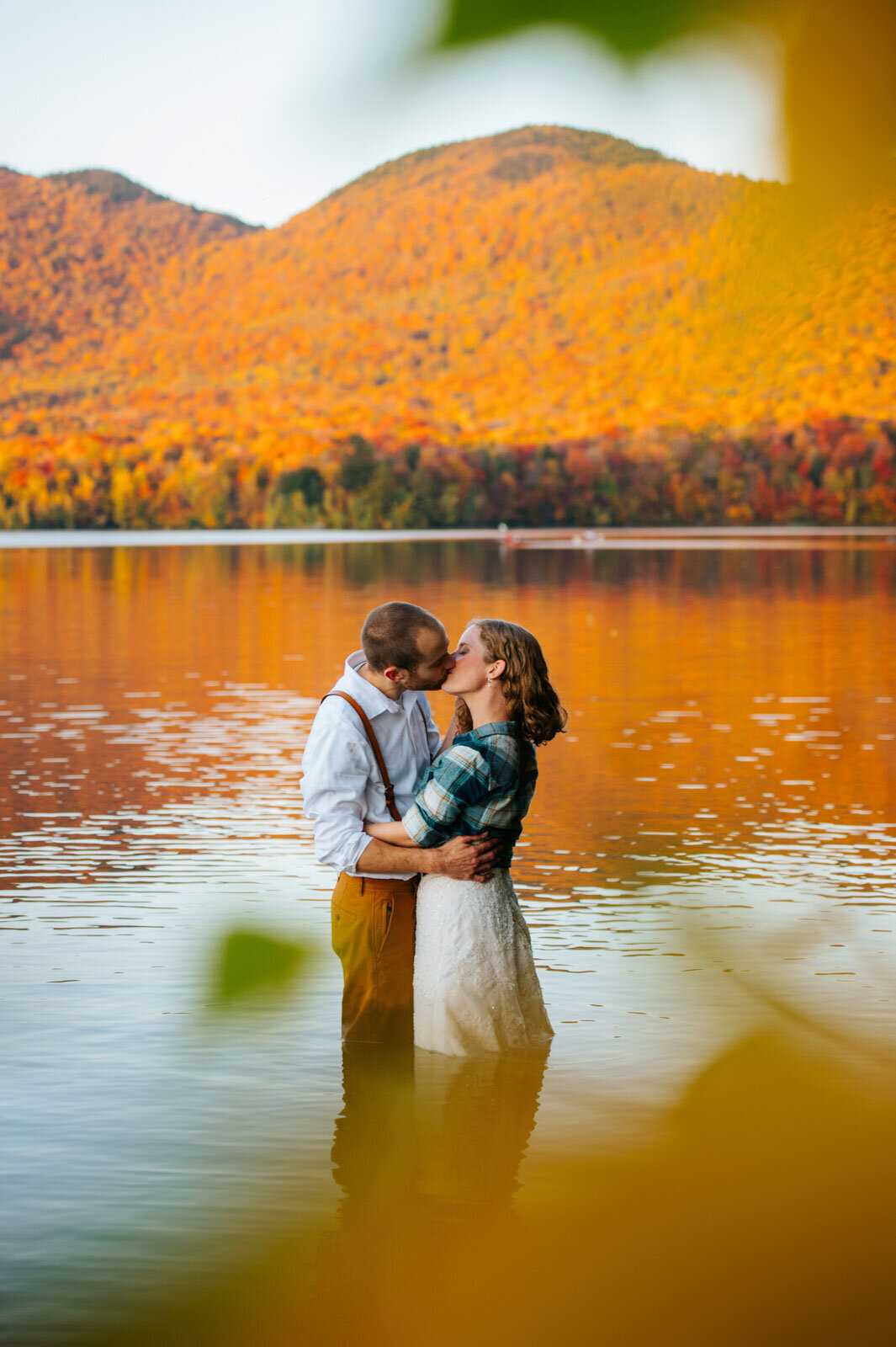bride and groom stand in the water kissing at fall adventure elopement in chittenden vermont