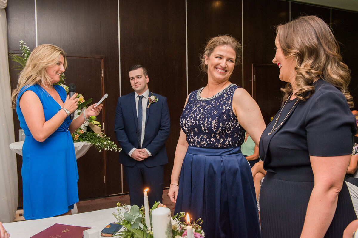 Gay brides wearing navy wedding dresses at ceremony in hotel
