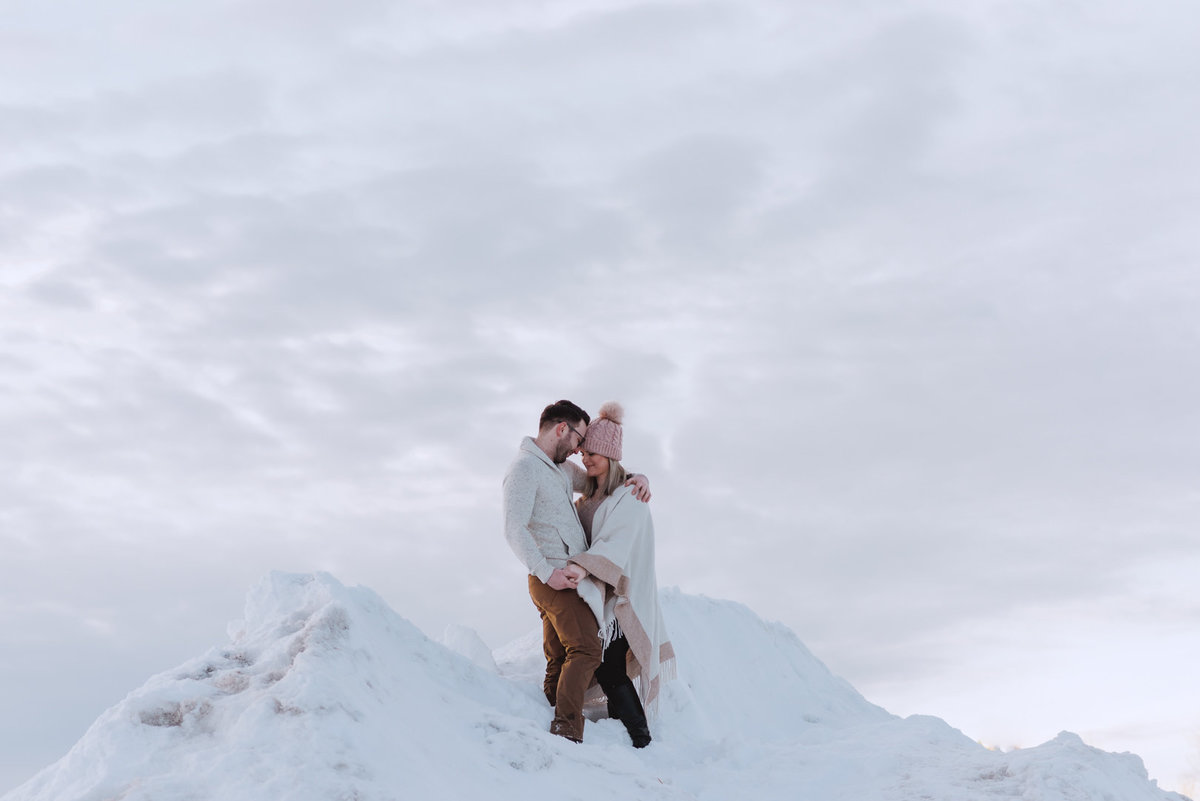 engaged couple at the top of a snowy mountain at sunset