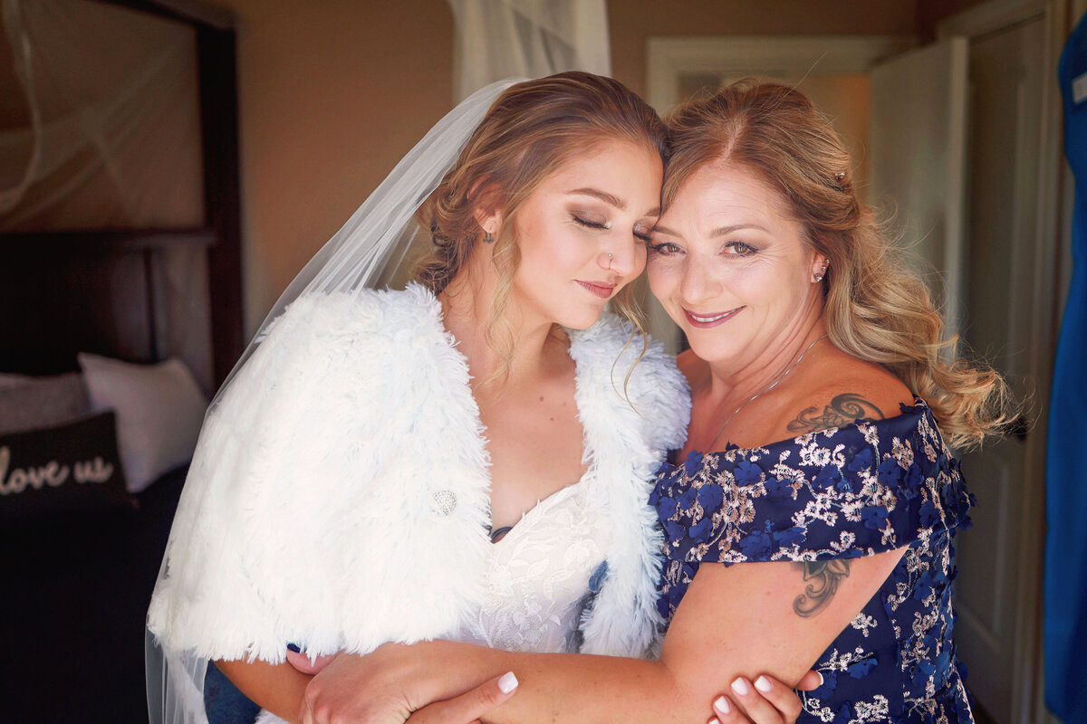 A bride and her mother share a sweet moment, hugging each other and enjoying the moment she is ready to walk down the isle.
