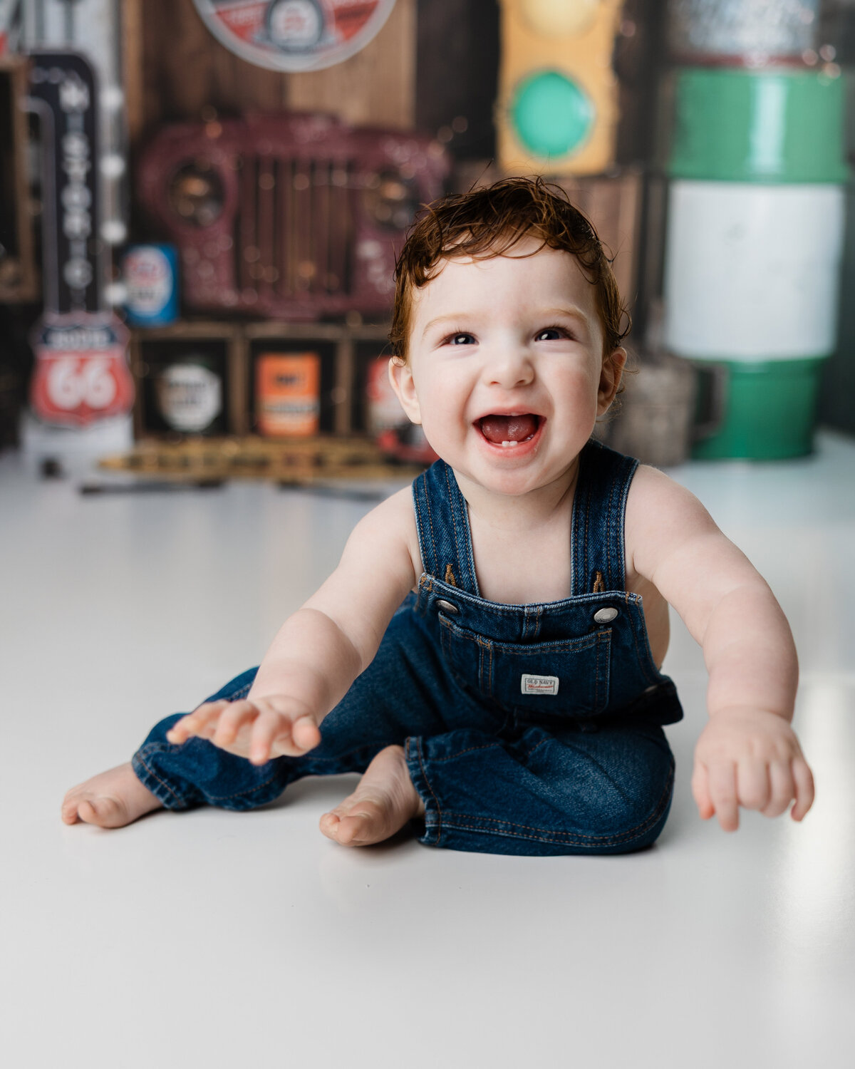 One-year-old boy laughing and leaning forward during his cake smash session, styled with retro automotive props.
Photograph by Yucaipa cake smash photographer Kaitlyn Dawn Photography.