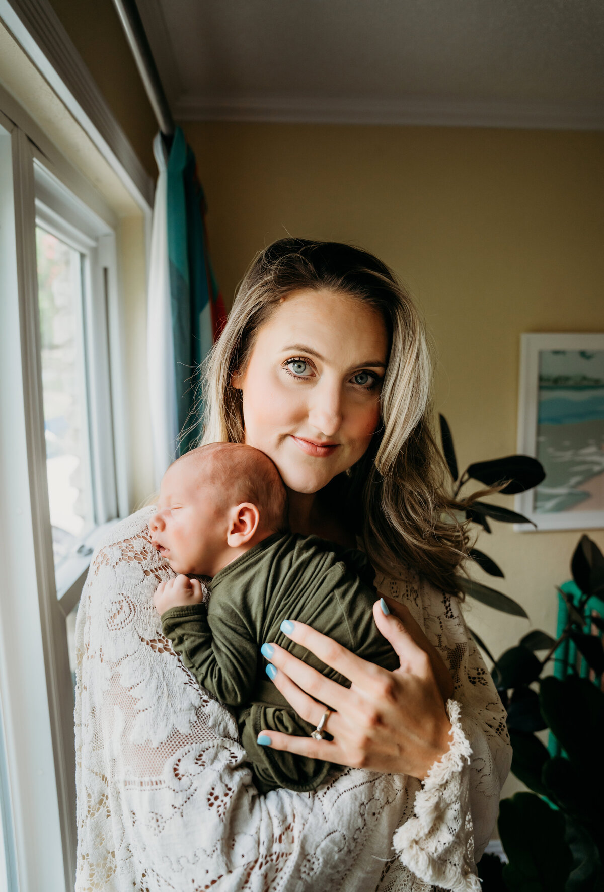 Newborn Photographer, a mother stands in her living room holding her newborn baby son