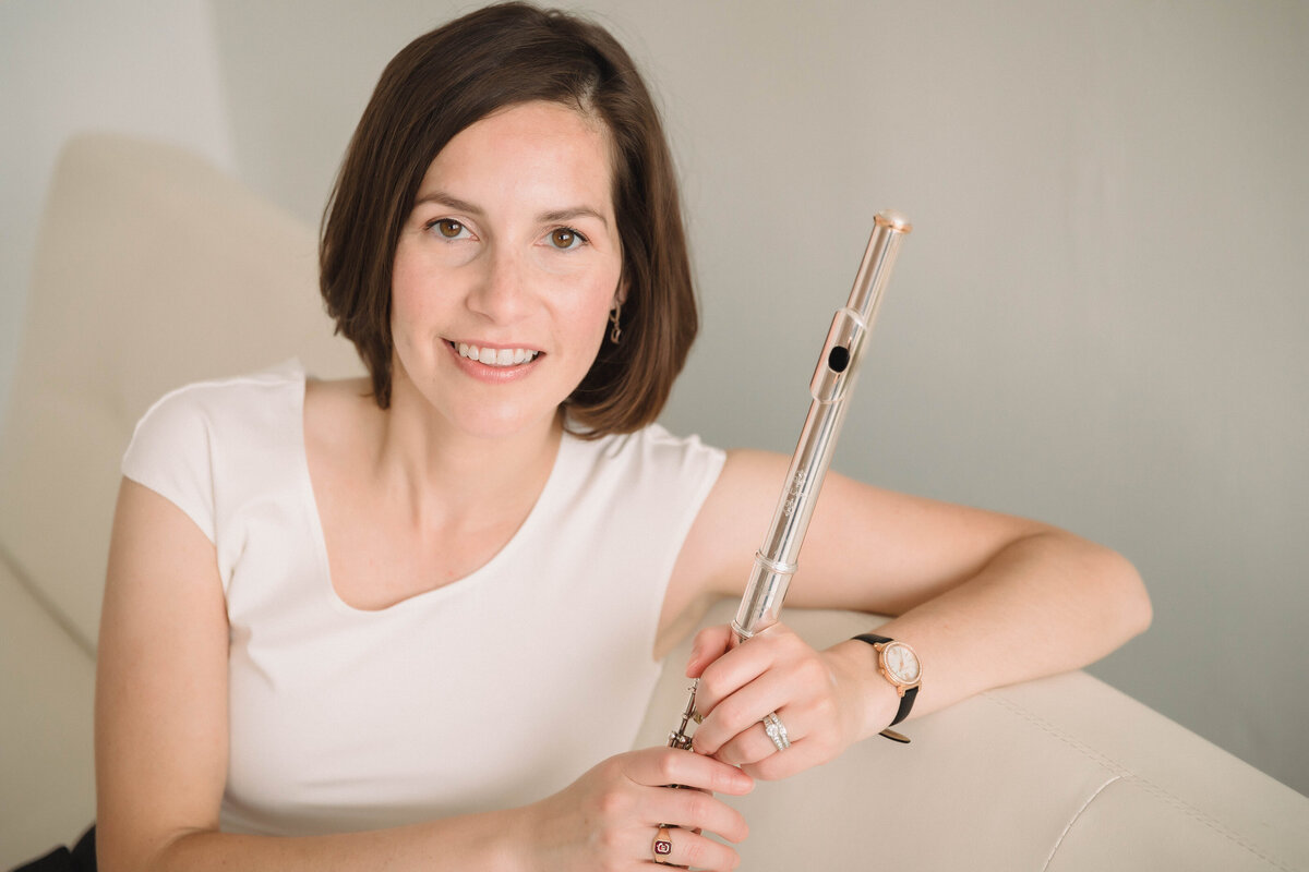 SarahWSarah Weisbrod, Flutist & Teaching Artist, Standing with Flute in on a Couch
