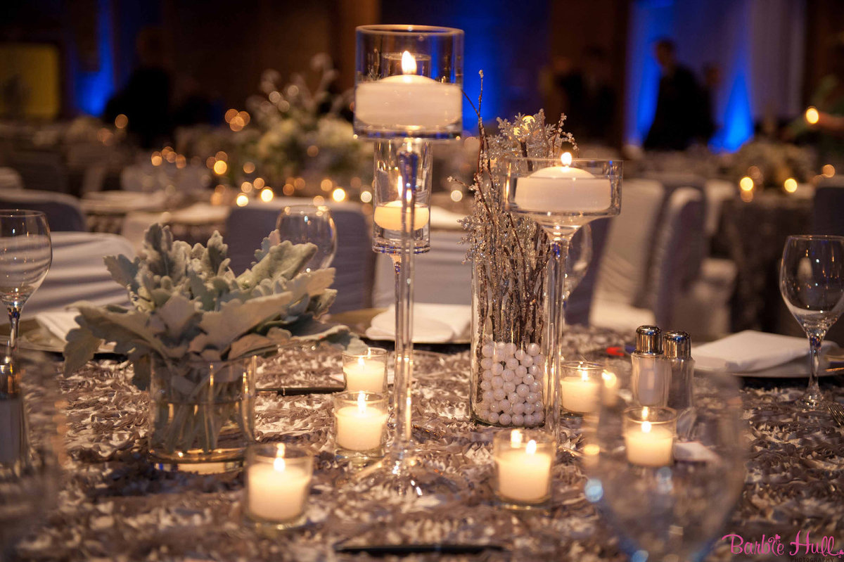 winter centerpiece for corporate holiday party  on silver linen, candles, and silver Dusty Miller foliage