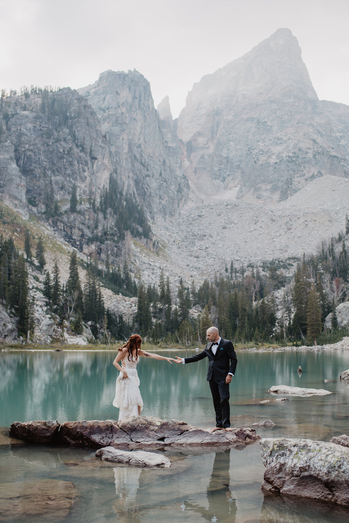 Jackson Hole Photographers capture couple holding hands while standing on rock in Grand Tetons