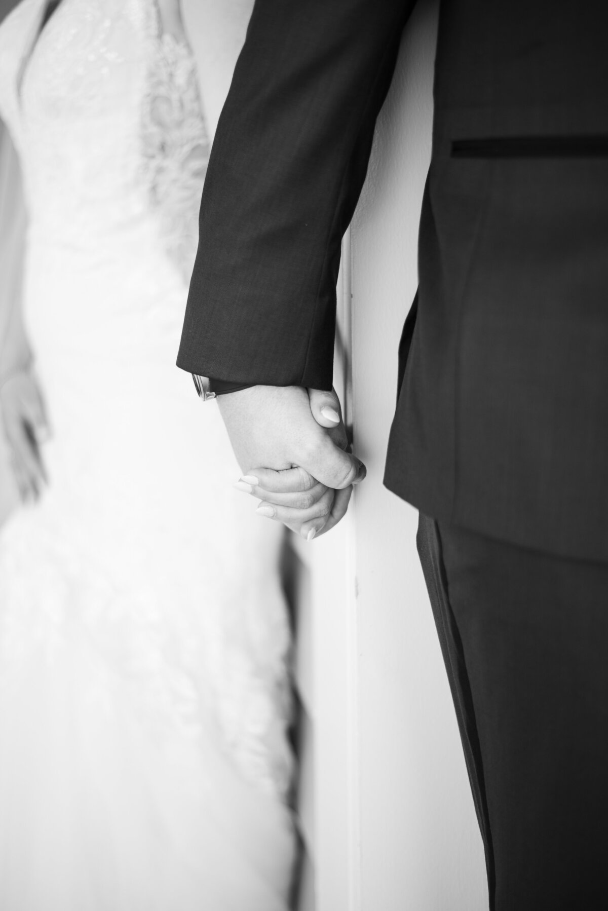 black and white detail image of bride and groom holding hands before their wedding ceremony captured by denver wedding photographer