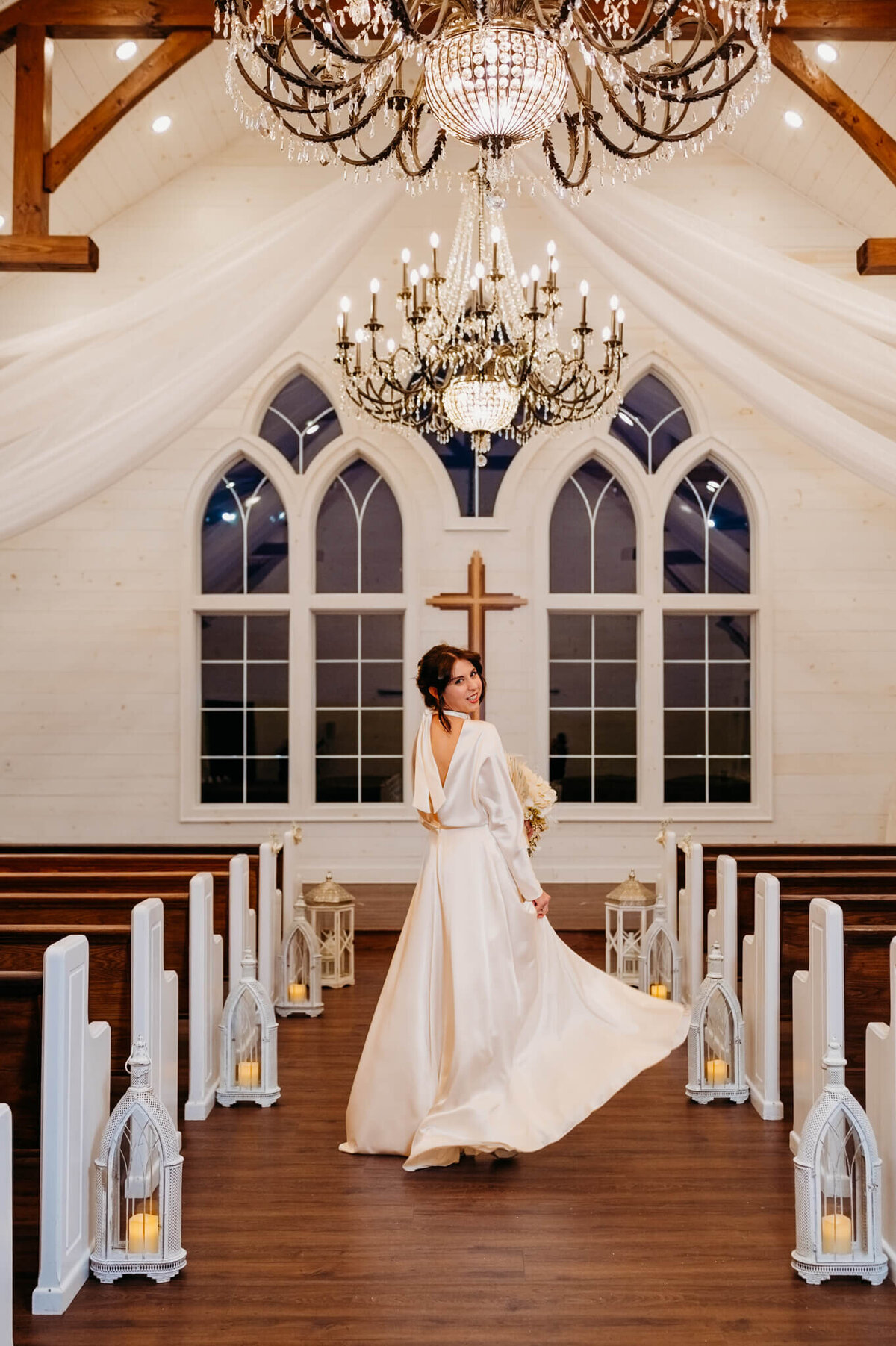 The bride spinning her dress inside of a chapel chandeliers