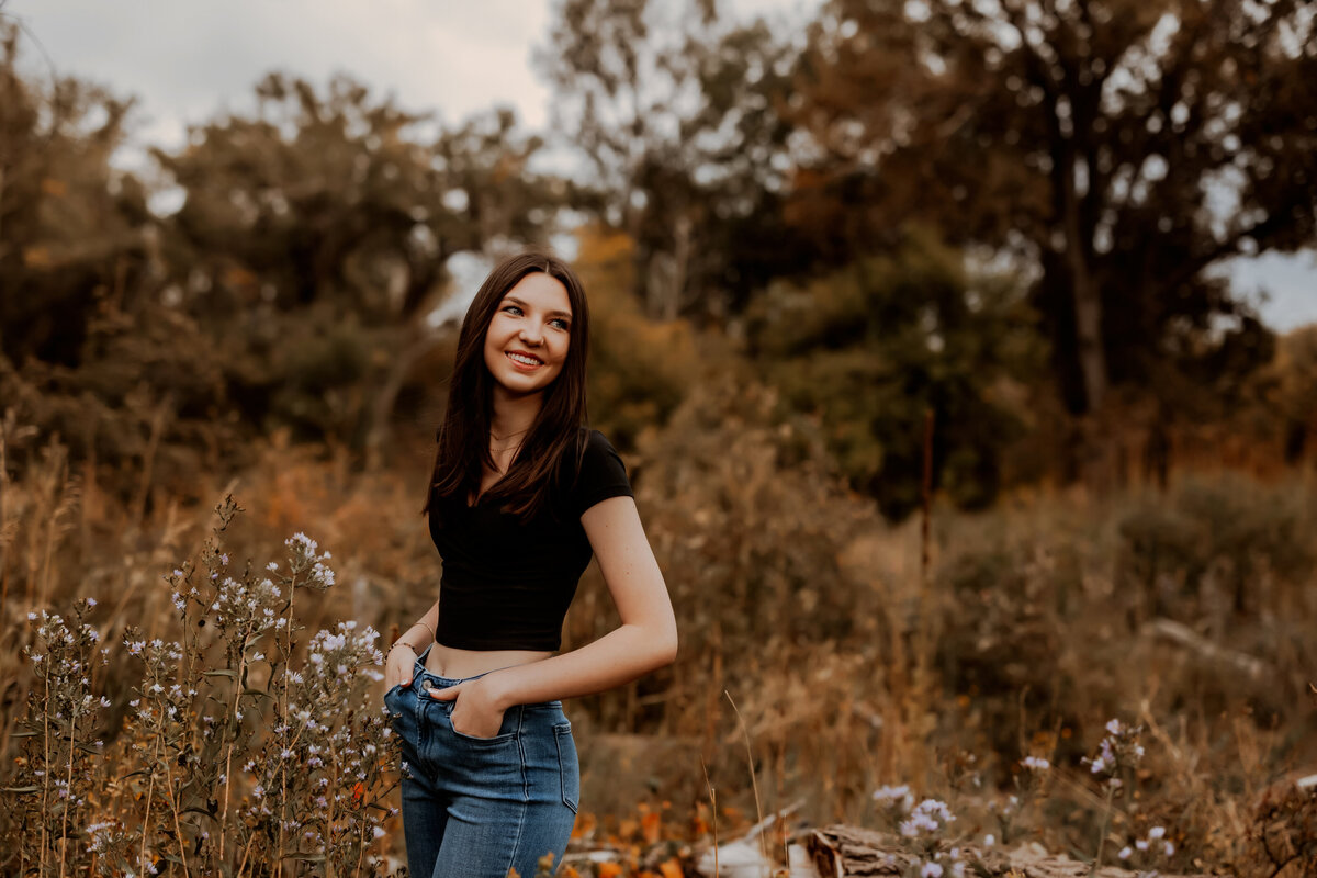 senior girl stands in fall wheat field in boulder colorado for senior photos