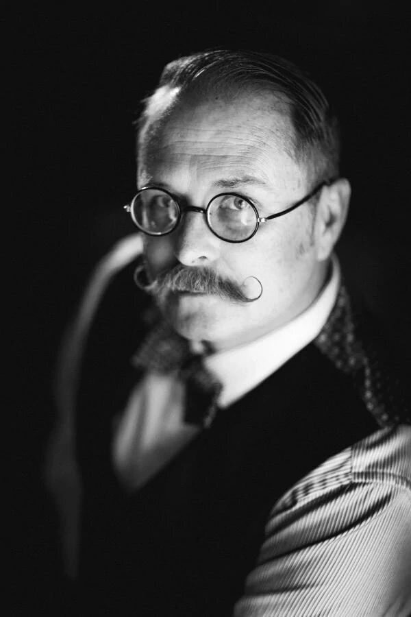 A man with a mustache and glasses looking up