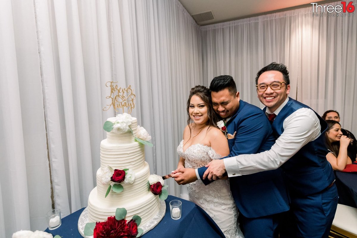 Bride and Groom get a little help from groomsman for cake cutting ceremony
