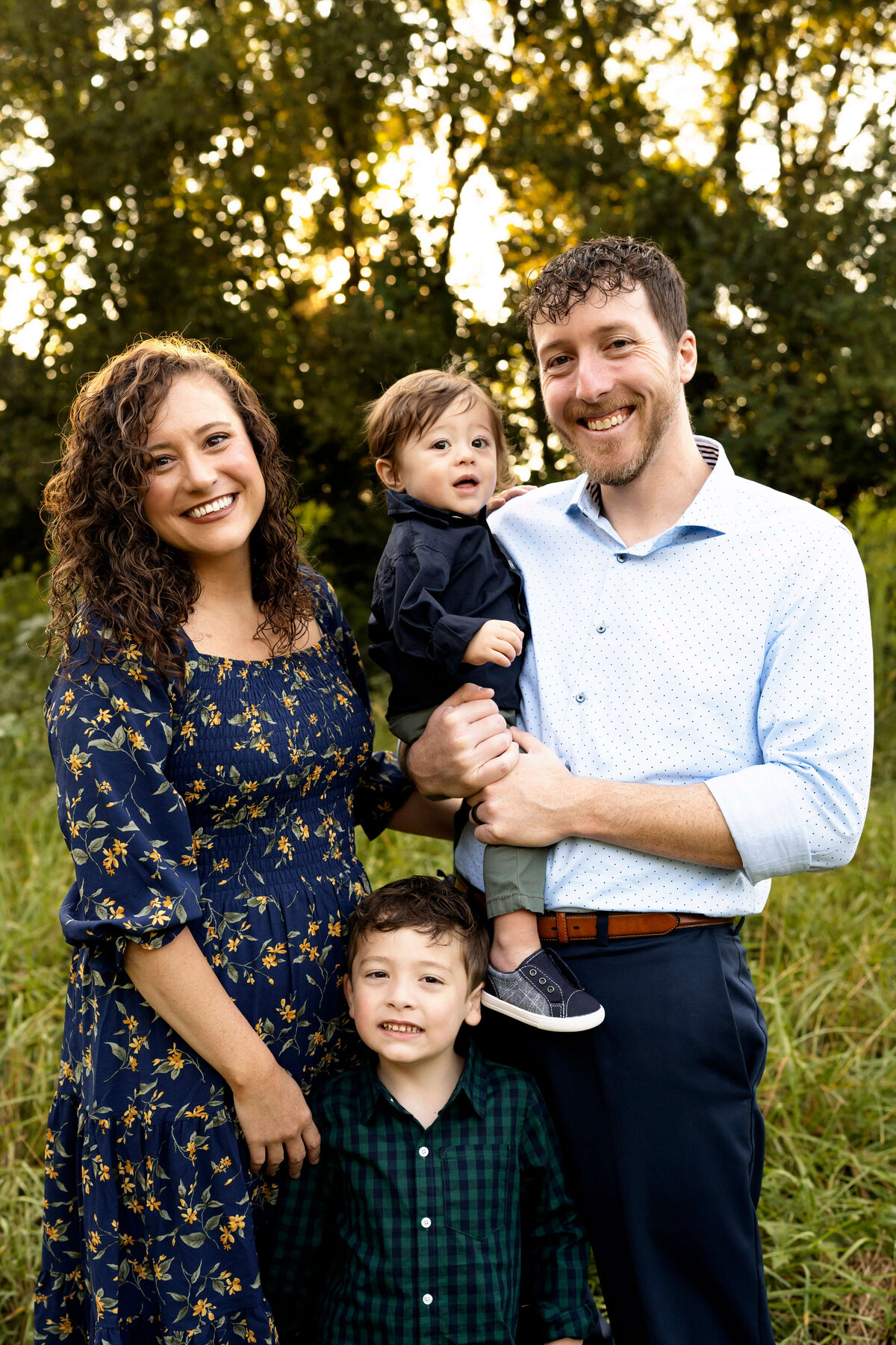 Family of four smiling at camera while standing in field