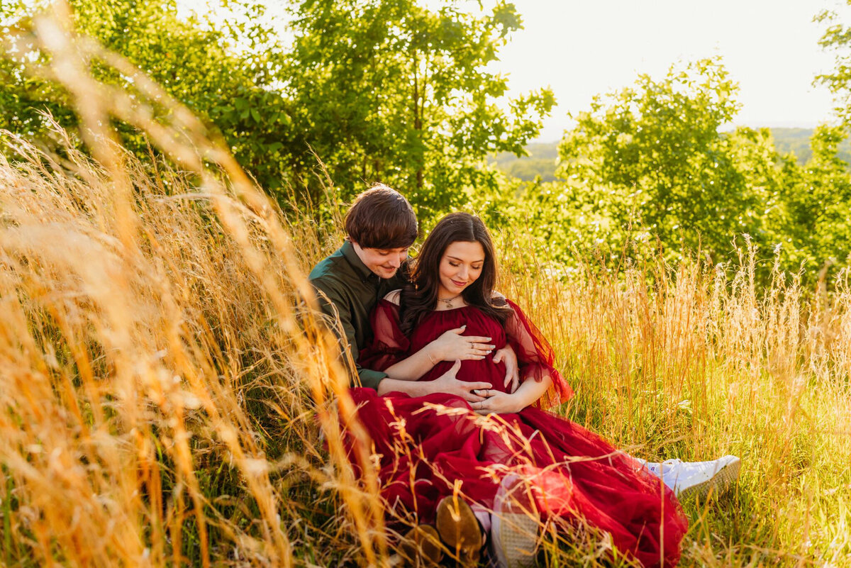 photo of pregnant woman sitting in field with her husband