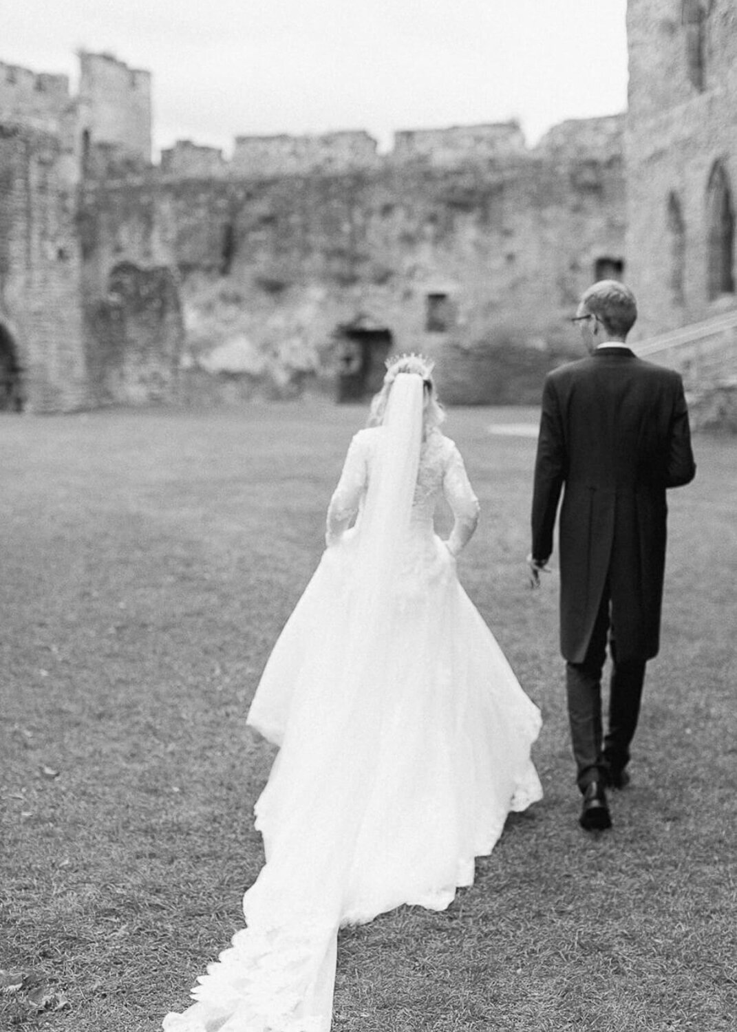 blurry black and white photo of bride and groom walking while bride showcasing long cathedral length veil