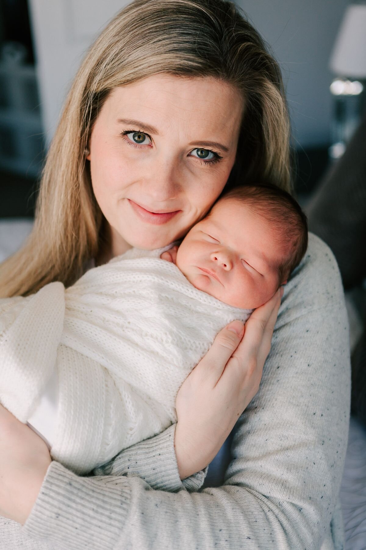 Newborn baby boy and mom face the camera for a portrait.