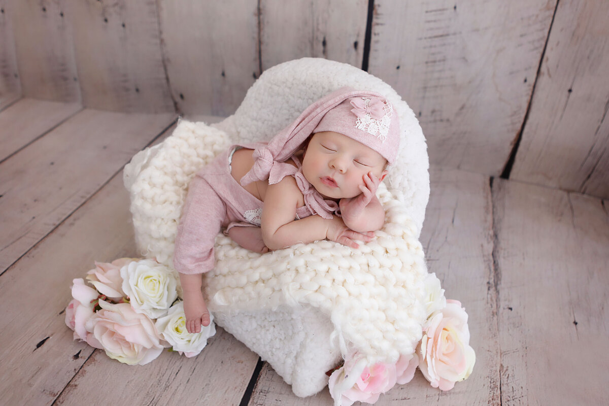 baby-in-a-pink-outfit-sleeping-peacefully-in-her-newborn-bed-prop