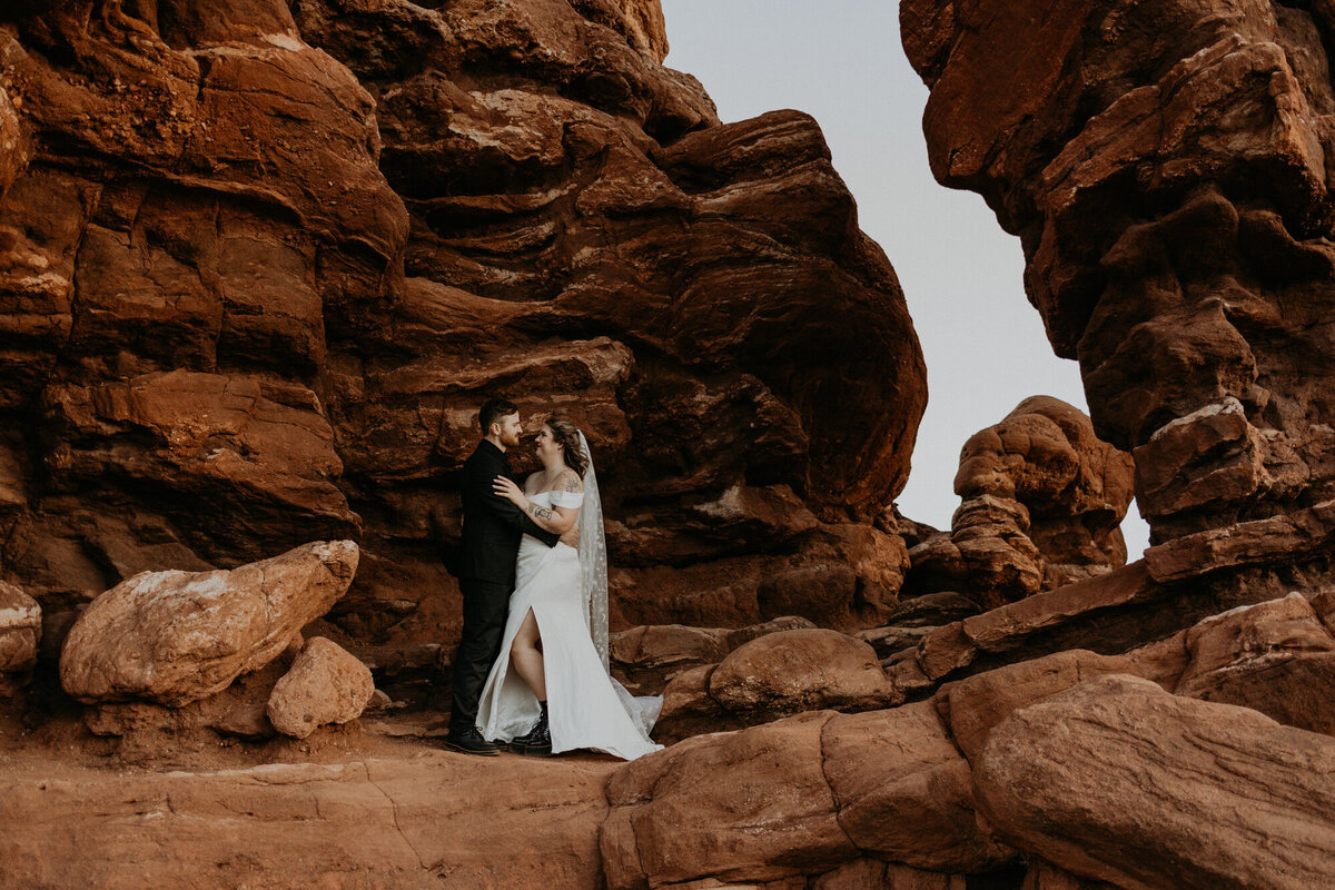 bride and groom standing together amungst the red rocks at garden of the gods