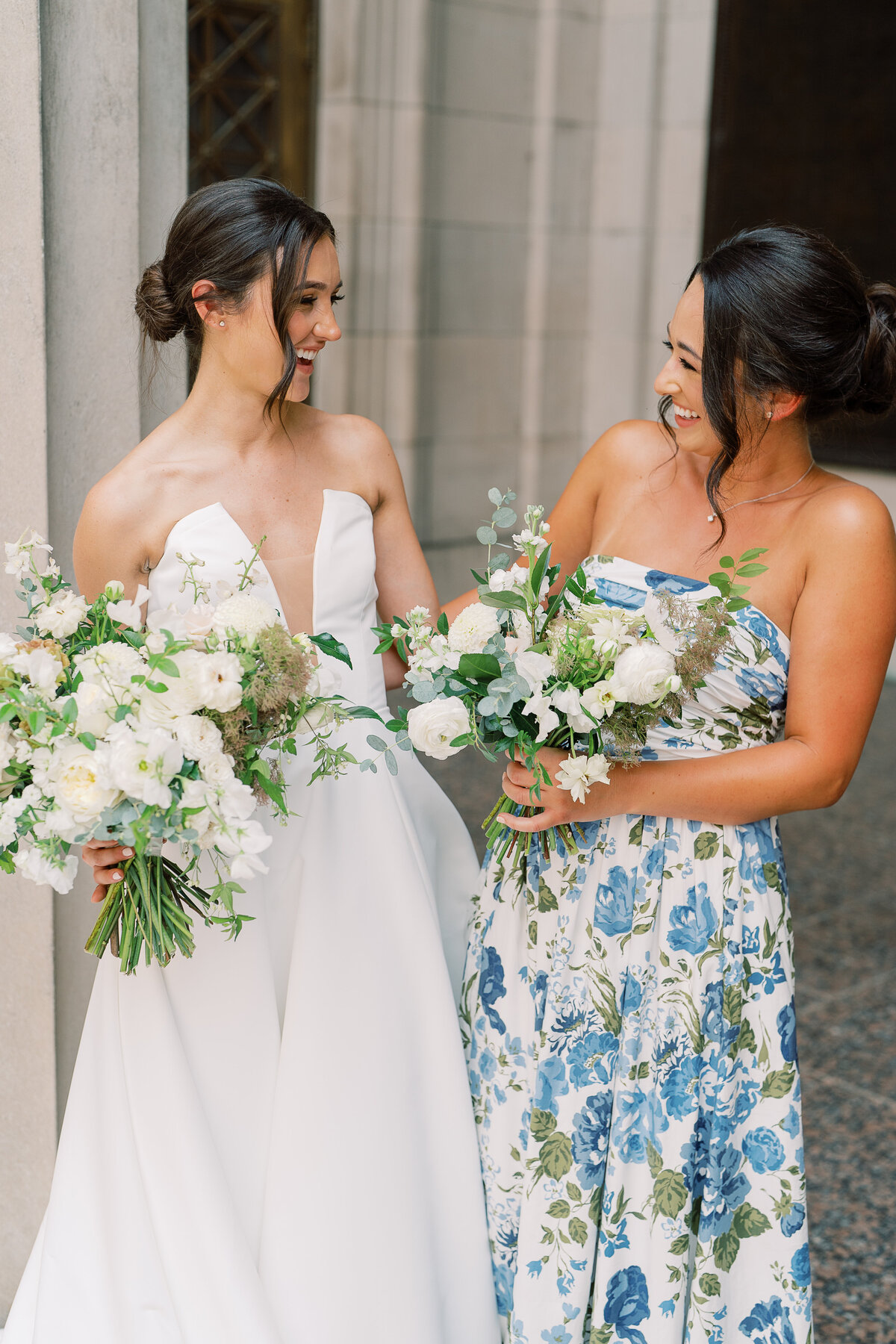 Dainty white and green bridesmaids’ bouquet for a summer wedding in downtown Nashville. Floral colors of white, cream, taupe, and champagne composed of roses, cosmos, zinnias, smoke bush, and ranunculus. Florals paired beautifully with garden-inspired bridesmaids dresses. Design by Rosemary & Finch Floral Design in Nashville, TN.